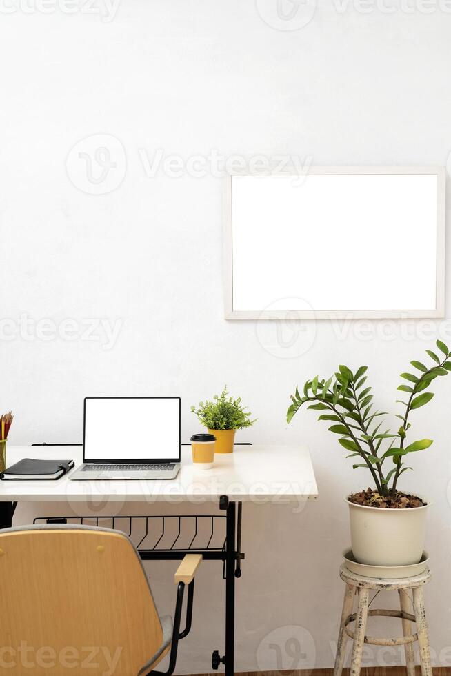 Photo of white blank screen computer laptop putting on black working desk and surrounded by stack of notebook