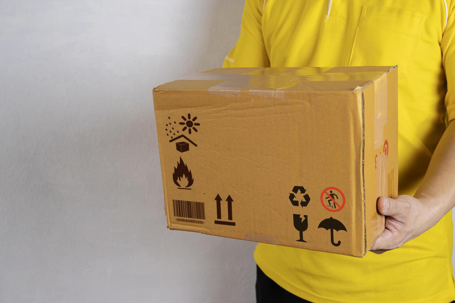Courier hand holding brown box isolated on grey background. Detail of delivery photo