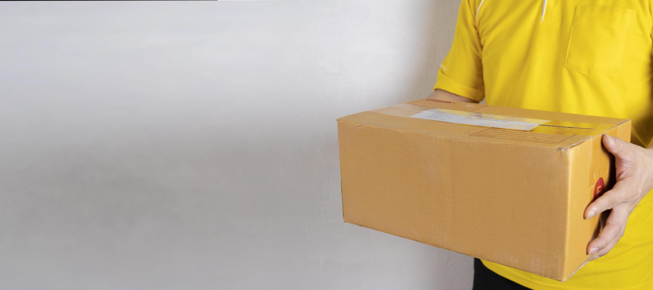 Delivery man in orange uniform handing a parcel box over to a customer, courier service concept photo