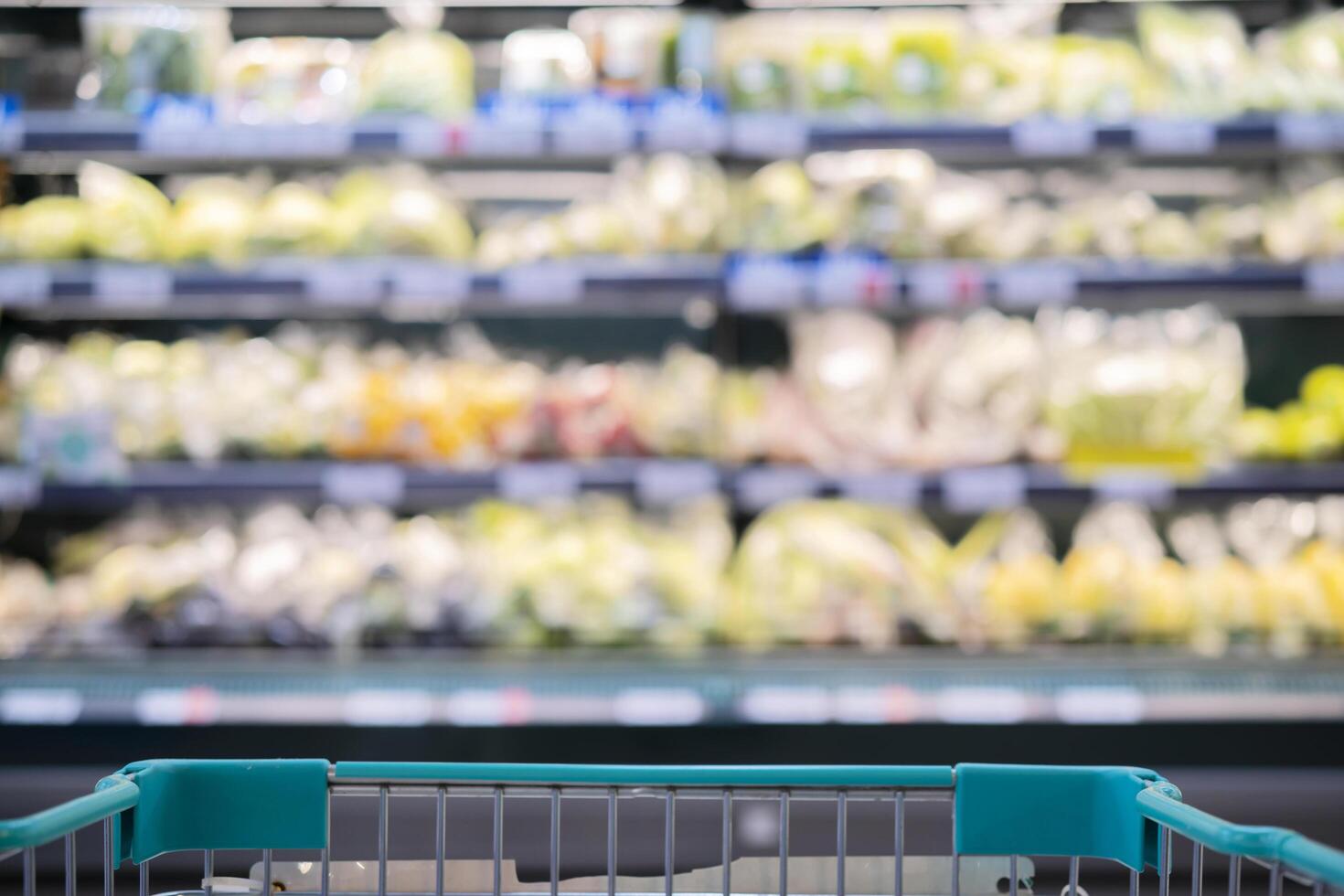 Supermarket aisle with empty red shopping cart. photo