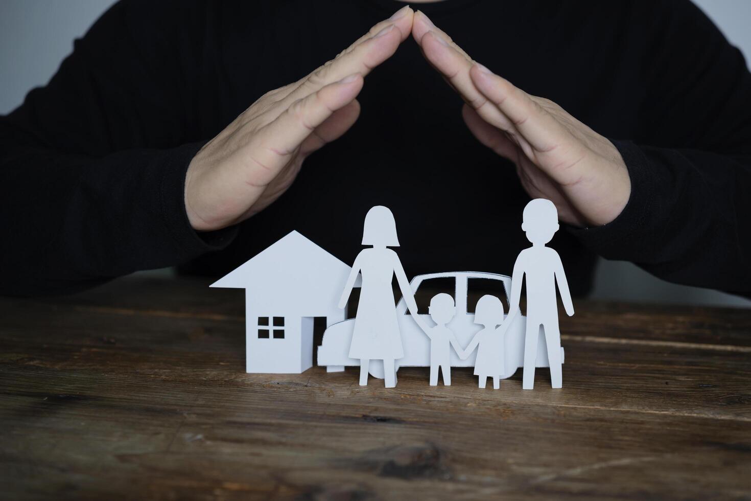 Concept of insurance with hands over a house, a car and a family photo