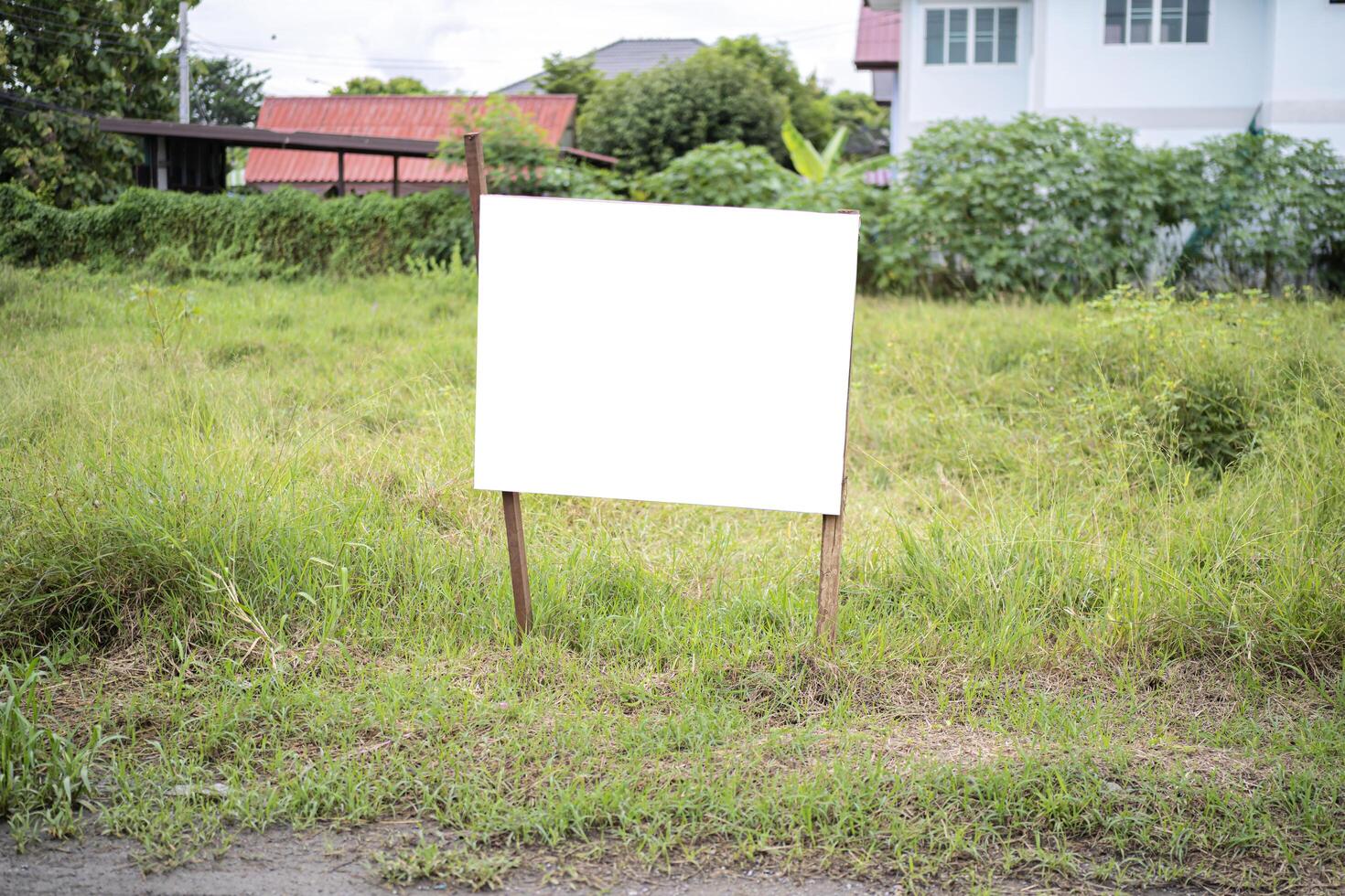 Blank white empty mockup template of a real estate sign at front of a lot of vacant lan photo