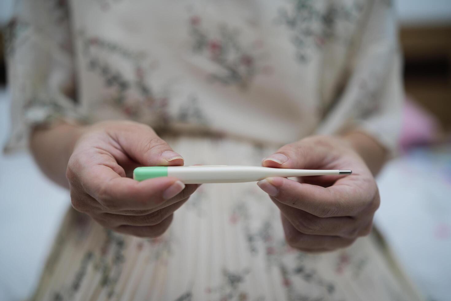 Fever during pregnancy. Pregnant girl holding thermometer measuring temperature photo