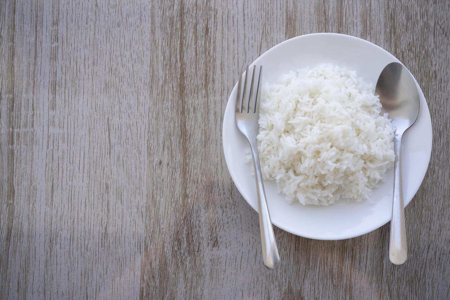 Thai fragrant jasmine rice scooped into served in a white plate on a brown wooden table. photo