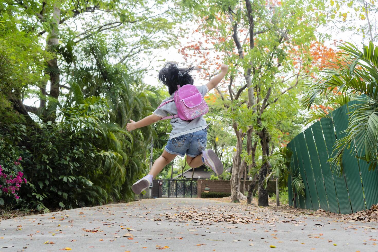 Back to school. Cute asian child girl with backpack running photo