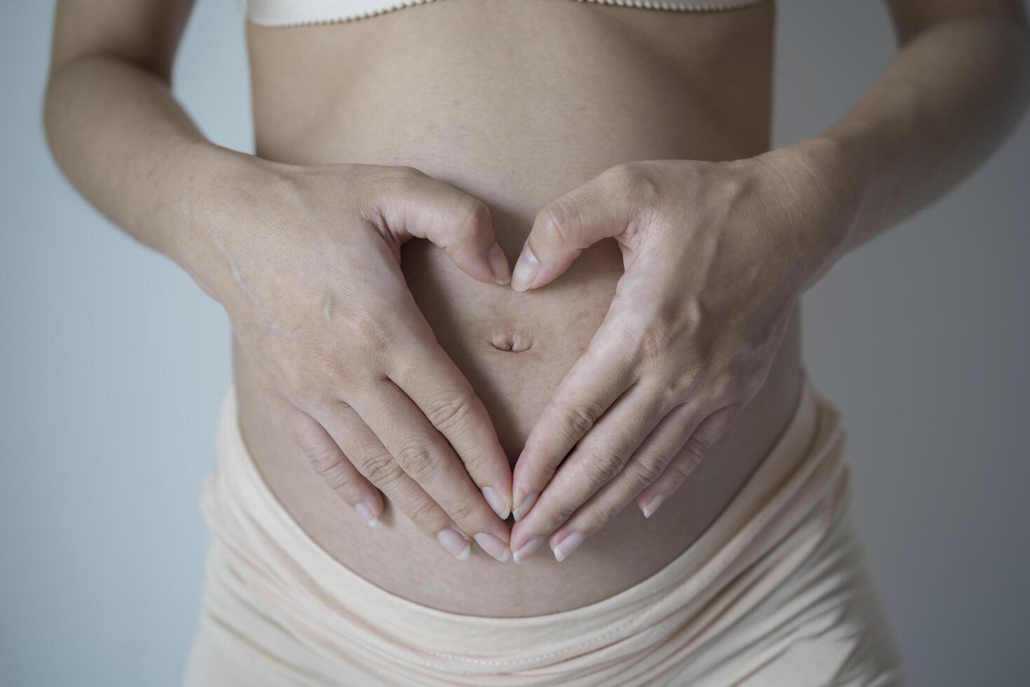 Beautiful young pregnant woman making heart with her hands photo