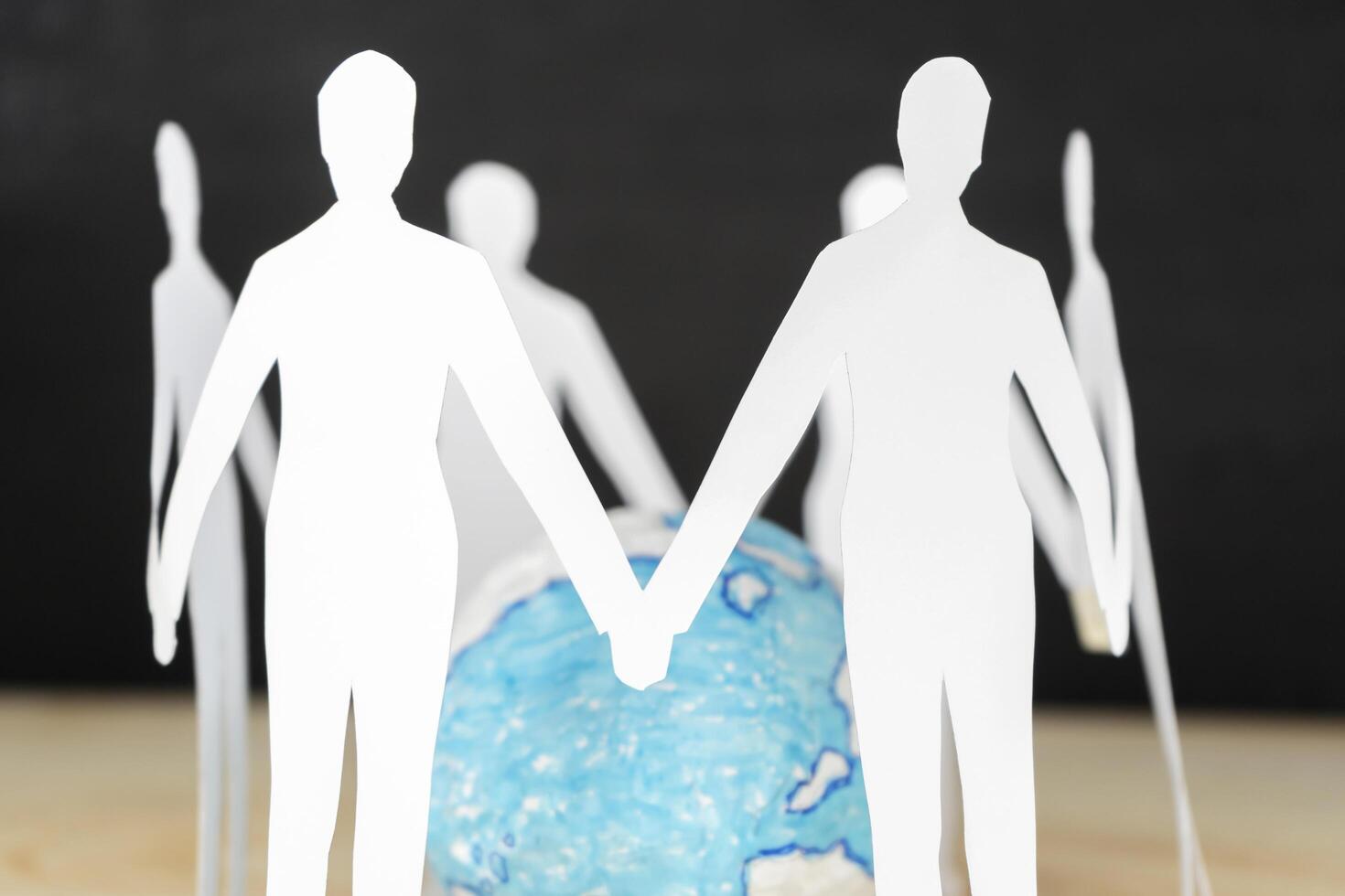 Paper people standing in circle around globe photo