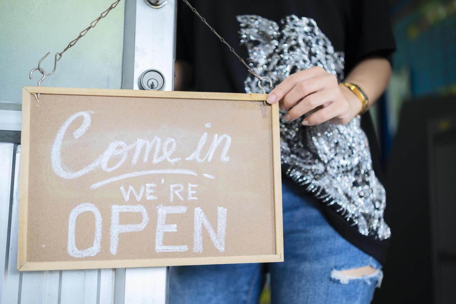 Store owner turning open sign broad through the door photo