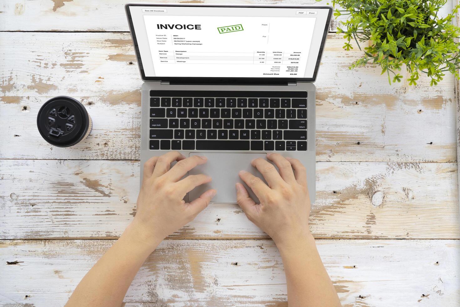 Close-up of businessman's hands working on invoice on laptop at office photo