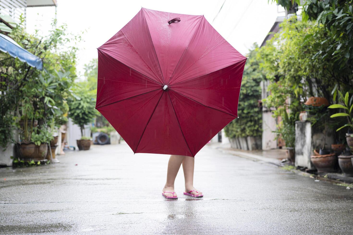A little girl holding a red umbrella stood in the middle photo