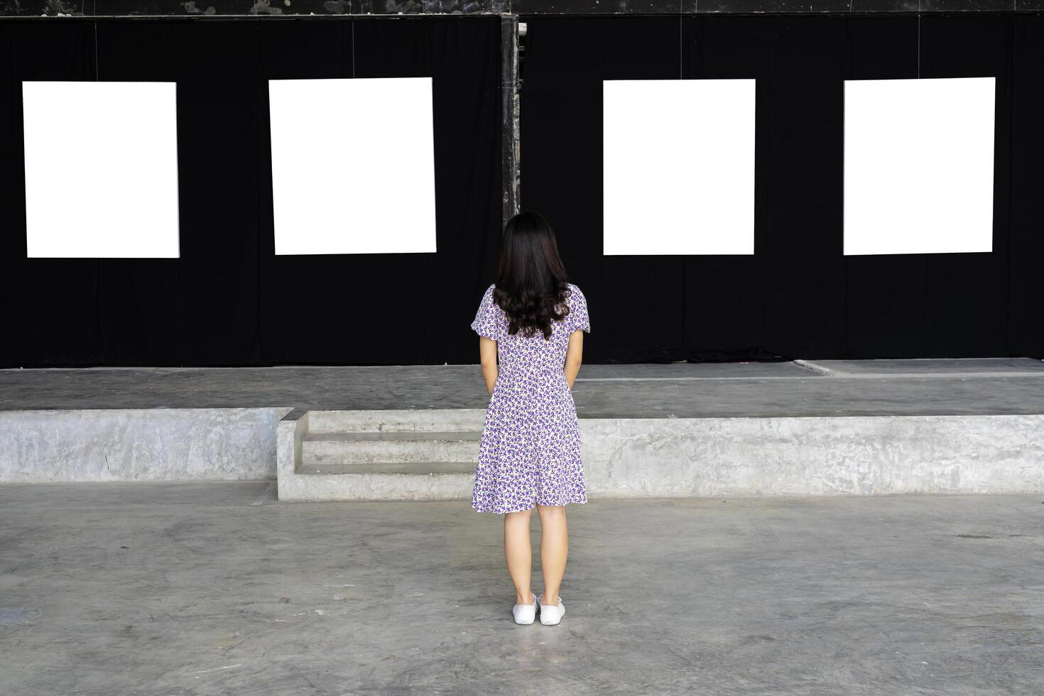 A woman standing and looking at a blank picture frame photo