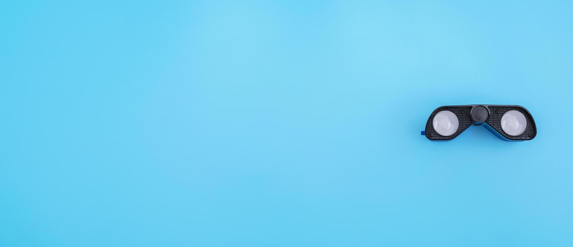 Binoculars on a light blue background. Banner. Flat lay photo