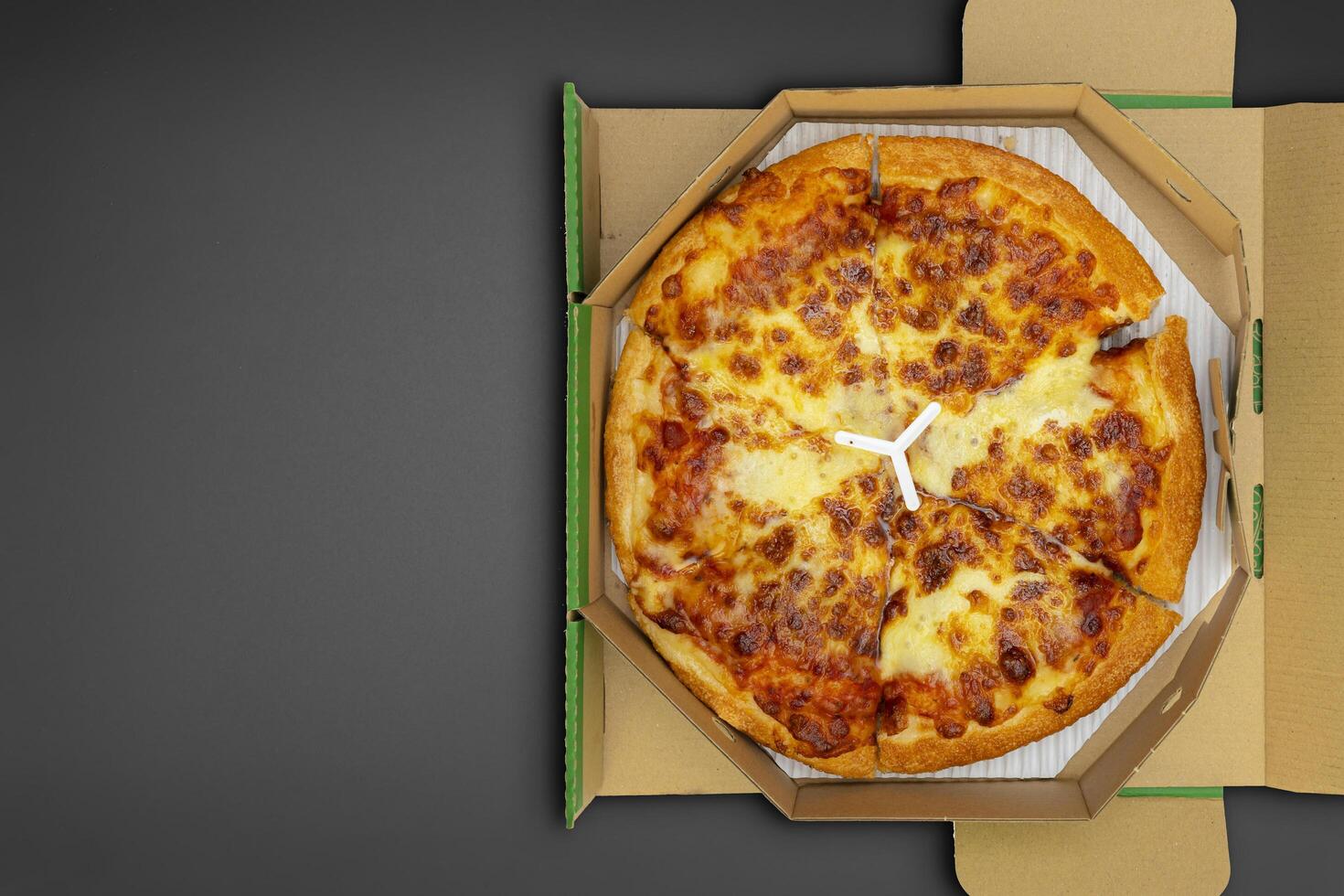 Pizza in a cardboard box on a black chalkboard background. Space for text. photo