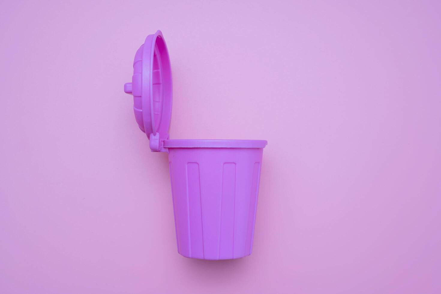 A pink mock-up trash can with an open lid and it is open on a pink background. photo