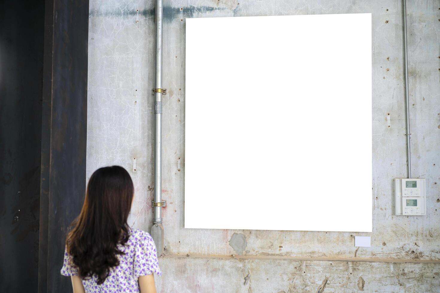 A woman standing and looking at a blank picture frame photo