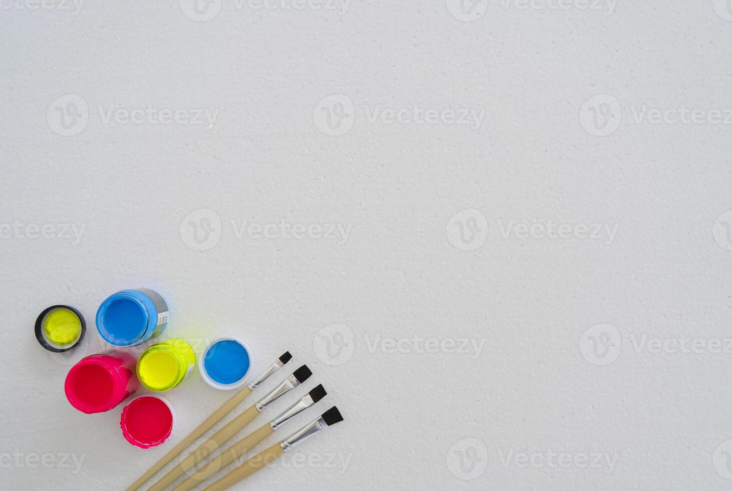 Paintbrushes and plastic paints are placed on a foam pad. photo