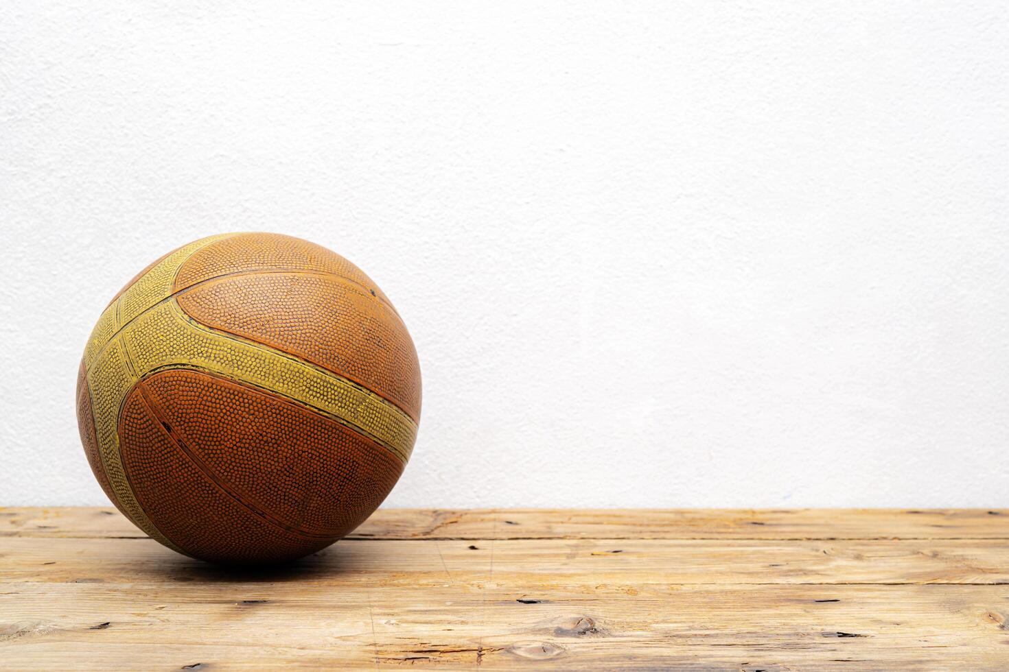 Basketball balls for sports and games are placed on a wooden table with white plaster photo