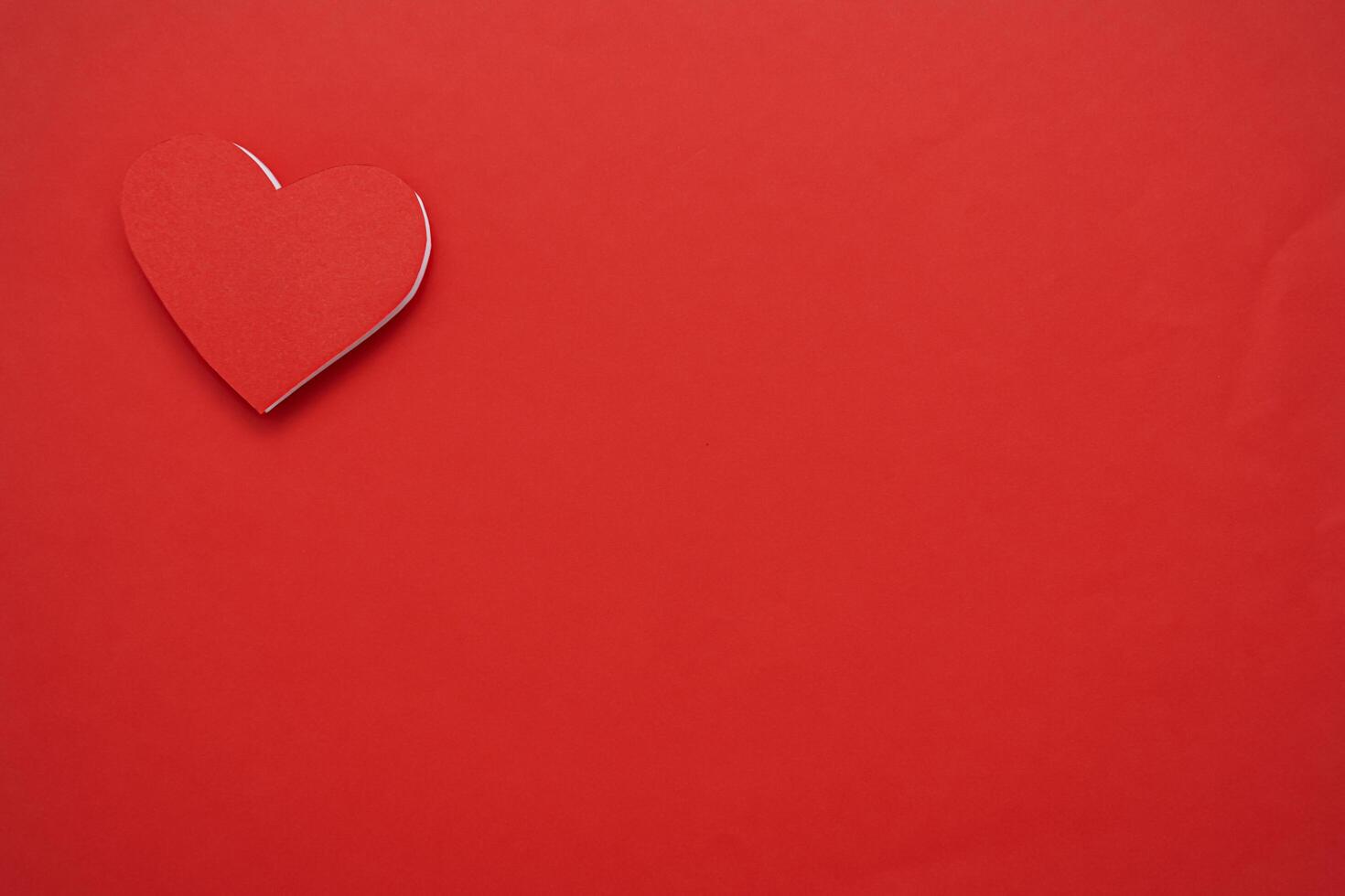 Red paper hearts isolated on red background. On the top left there is an empty space photo