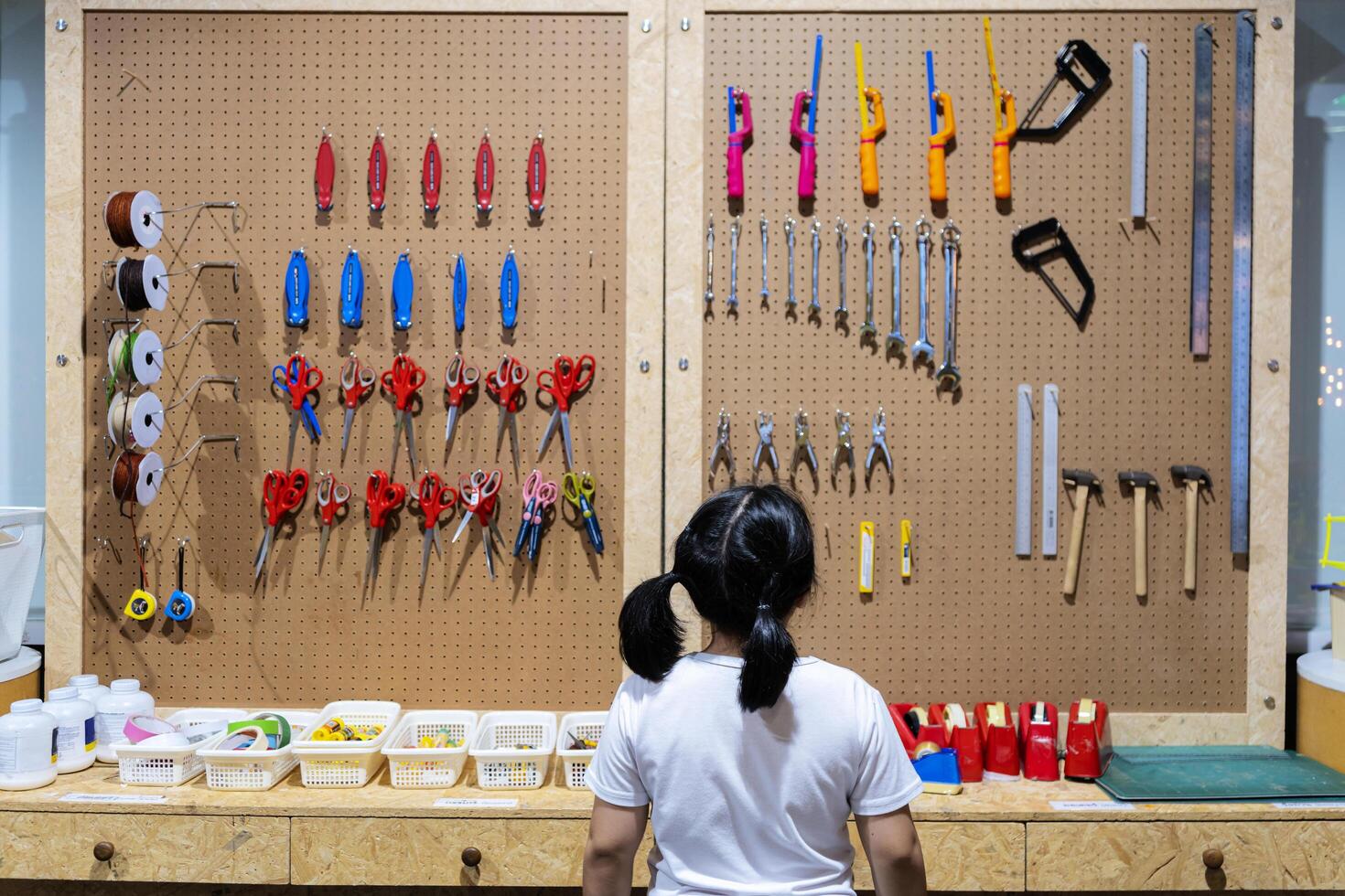 A girl is choosing tools on the table and board. Workshop scene concept photo
