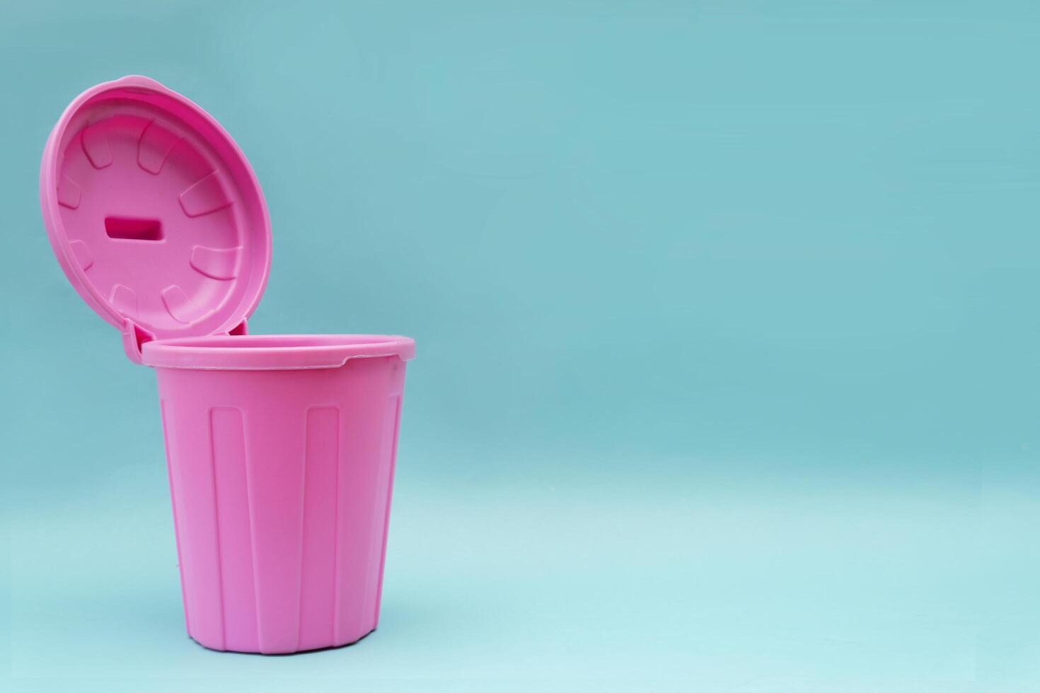 A pink mock-up trash can with an open lid and it is open on a blue background photo
