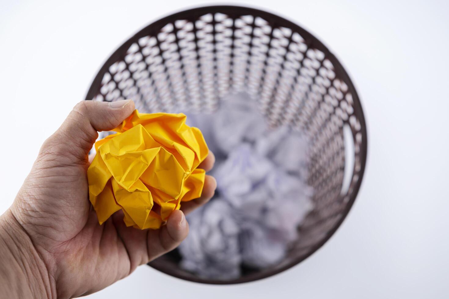 A hand holding yellow crumpled paper that is about to be thrown into the trash. photo