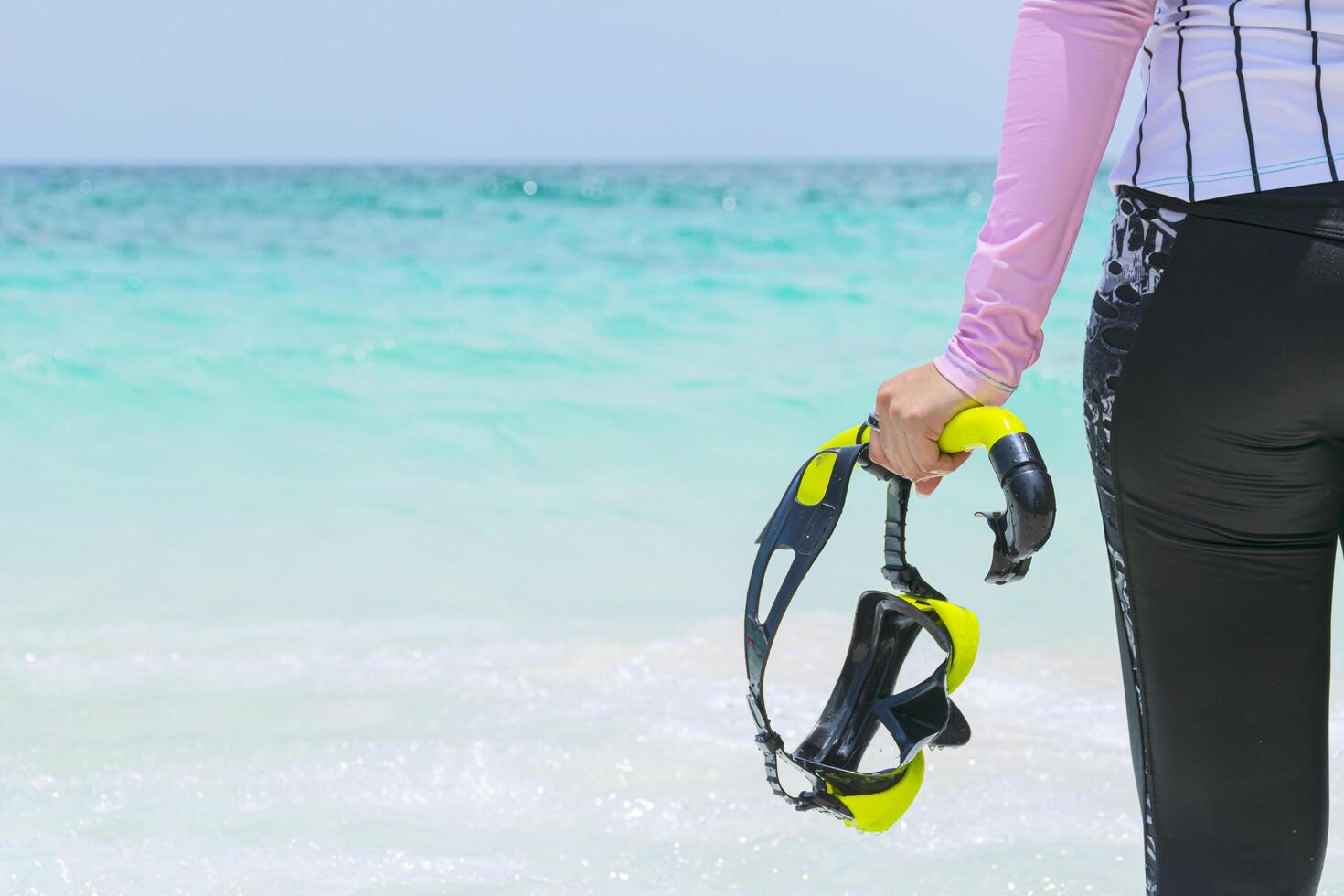 Women tourists holding diving equipment stands on a tropical beach ready to enter the water. photo