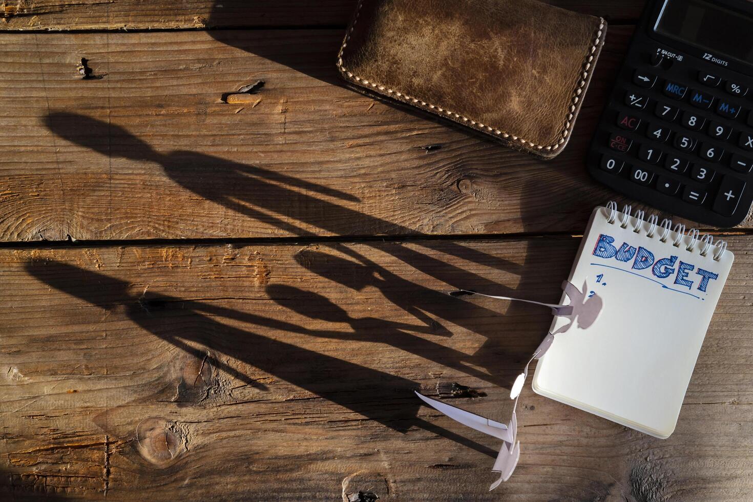 Budget planing concept. Top view of notepad with word budget, calculator, cup of coffee, family silhouette, pouch on wooden background photo