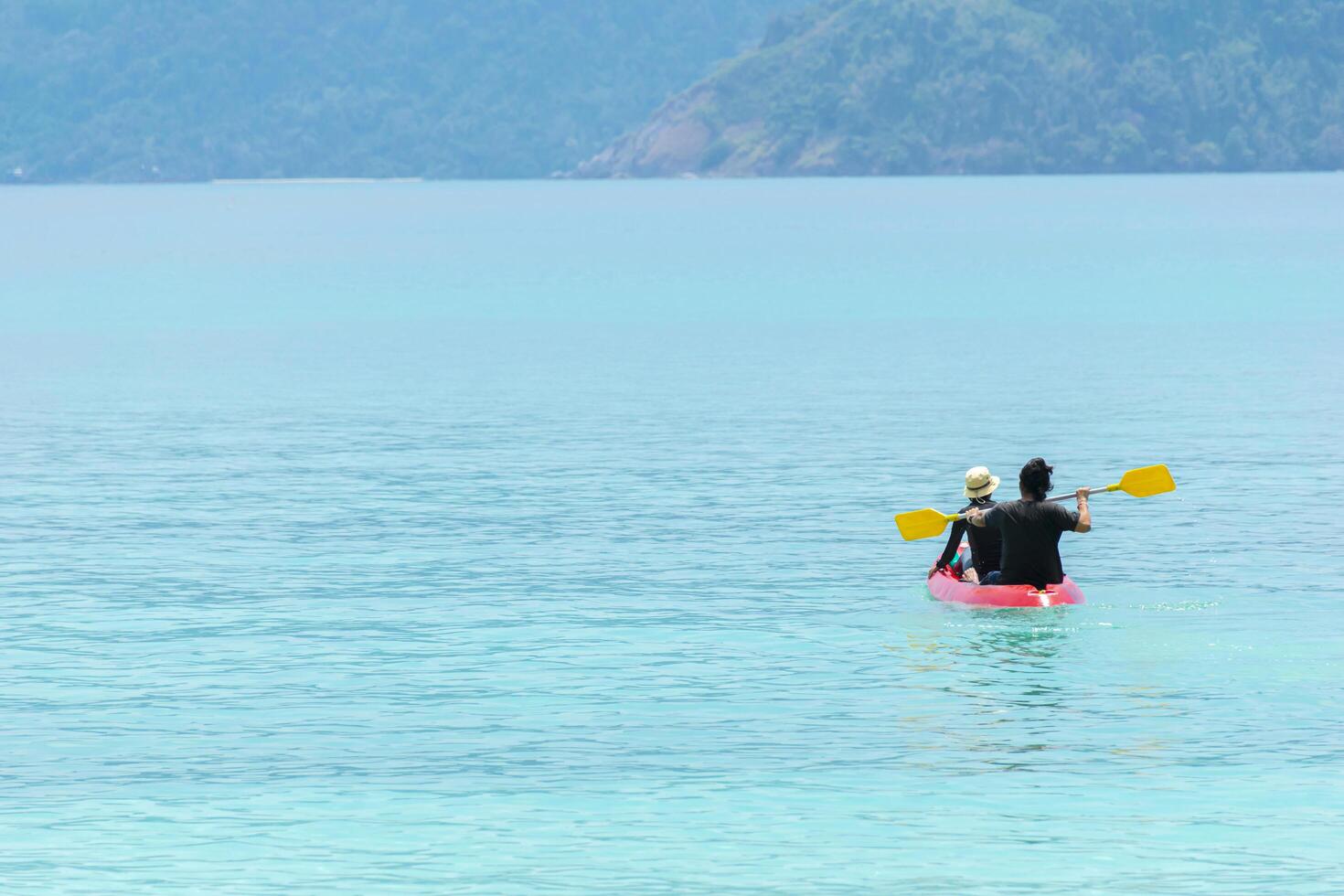 A couple helping canoe in a clear morning sea. Blue green sea photo