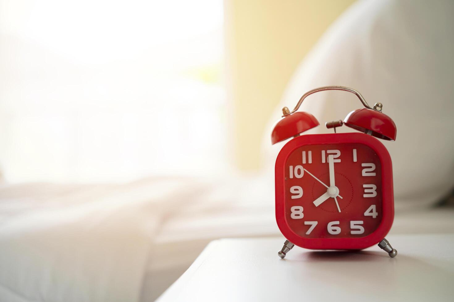 Red alarm clock stands on a bedside table in the room photo