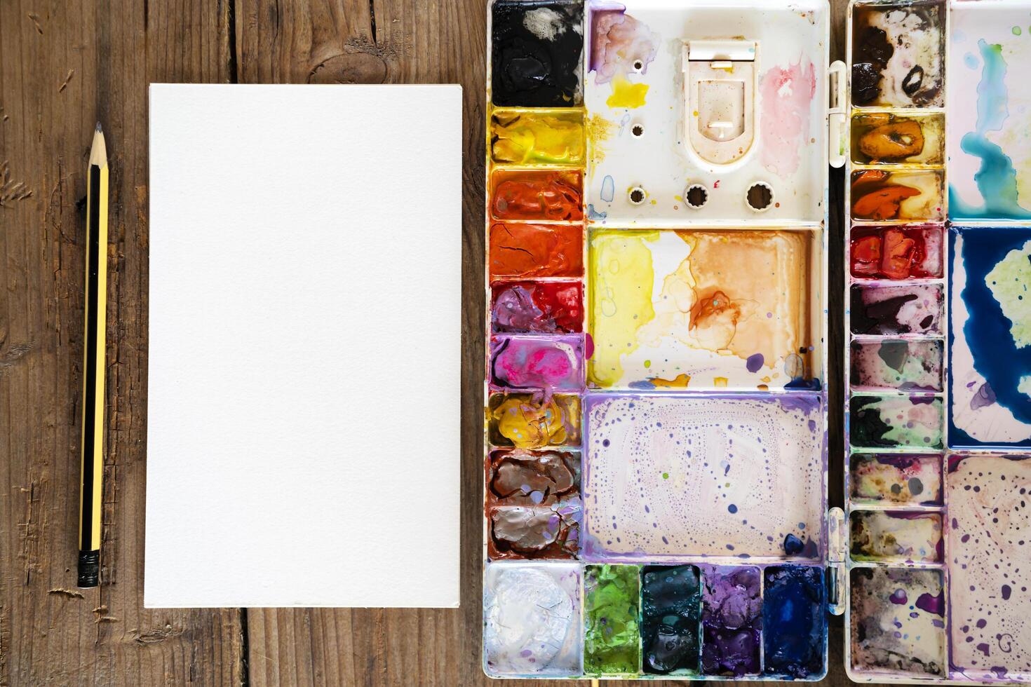 color in the palette water paints. A blank drawing paper and a pencil are placed on the side. photo