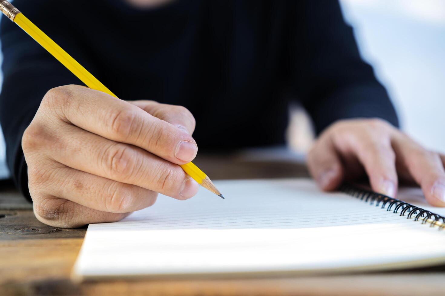 Closeup cropped hands of man writing day plan in notebook at the workplace at the computer. photo