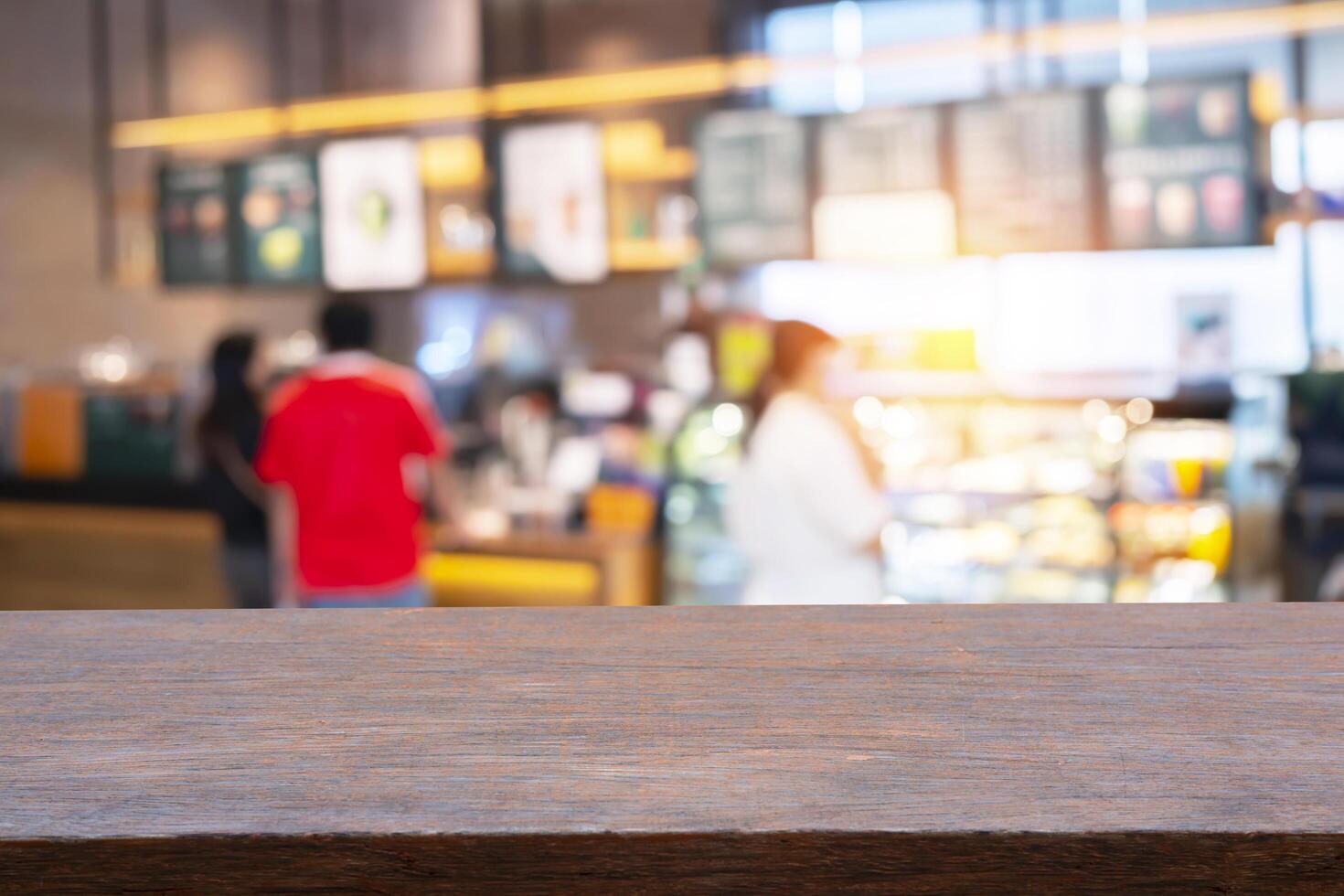 Empty wooden table top, blurred coffee shop and people sit on table blur background with bokeh image photo