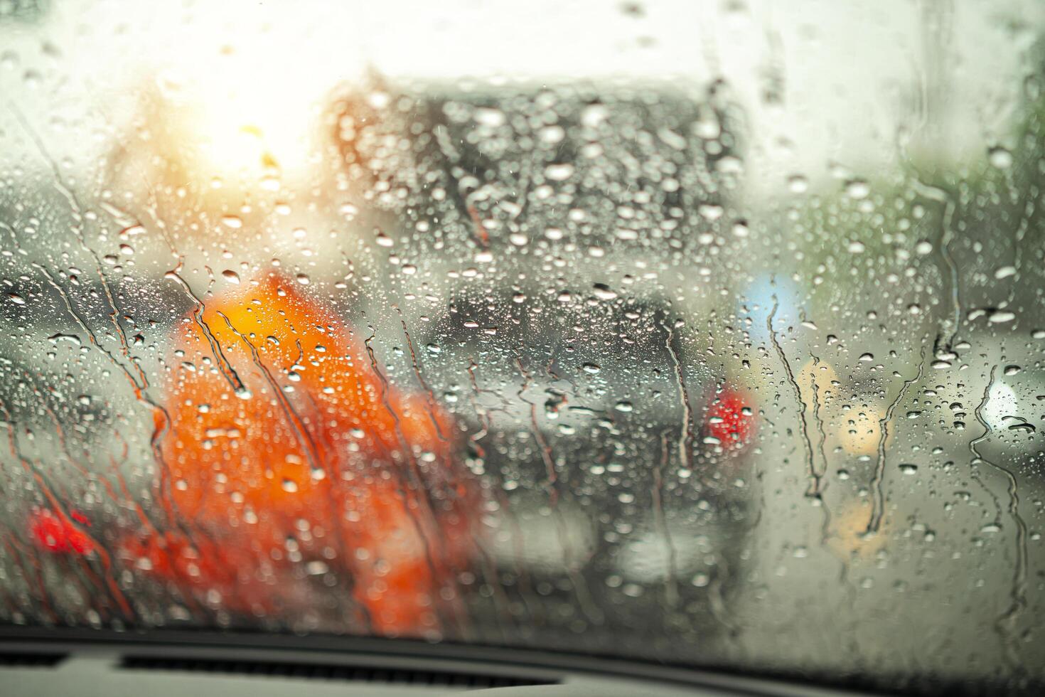 Street in the heavy rain. Water drops or rain in front of mirror of car on road or street. Driving in rain. Blurred background. photo
