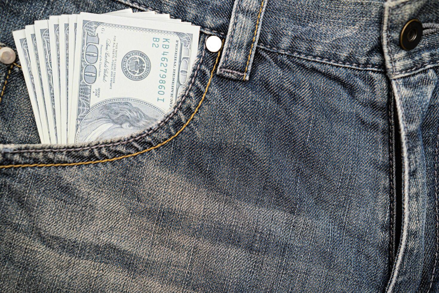 A dollar bill inserted in a jeans pocket. It is cash in a pocket and has cash on hand photo