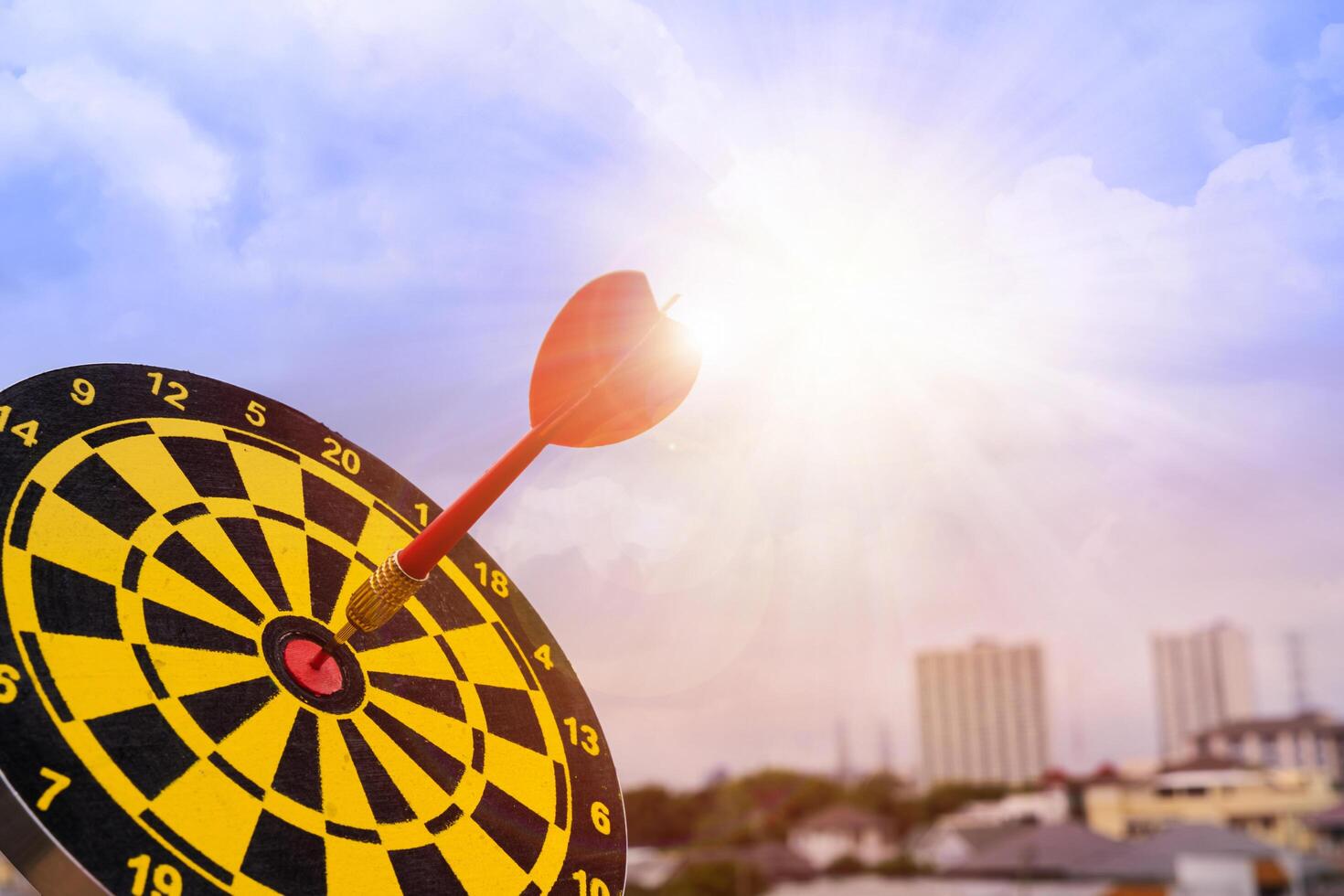 Red dart arrow hit in the target center of dartboard with sky background, Target hit in the center by arrows photo
