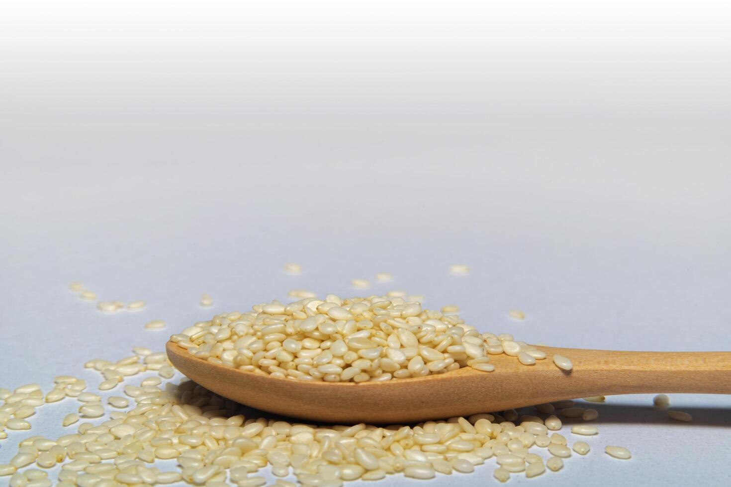 White sesame seeds or cumin in spoons on Gray isolated background photo