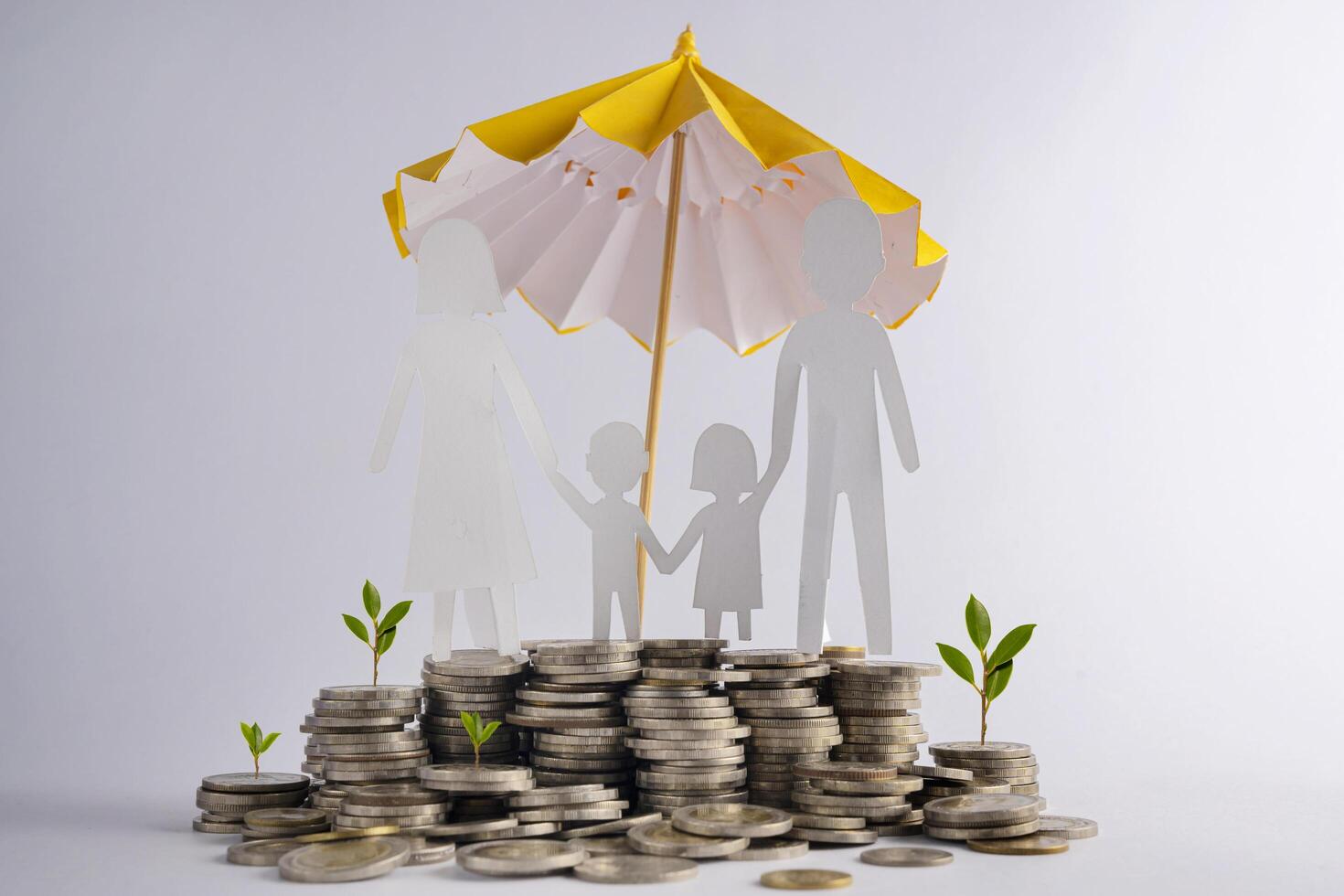 Stack of coins with family with protective umbrella on dark background, business idea and savings insurance concept. photo