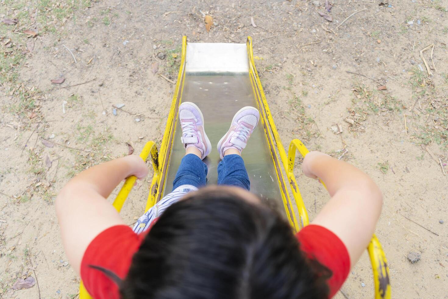 Cute asian child girl having fun to play slider in the playground in summer time photo