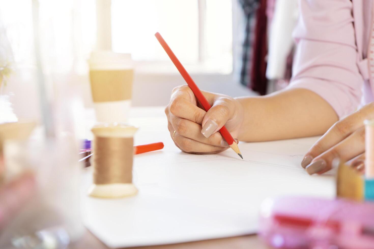 Asian women designers are using pencils to design works on paper, The sewing device is placed as an element. photo