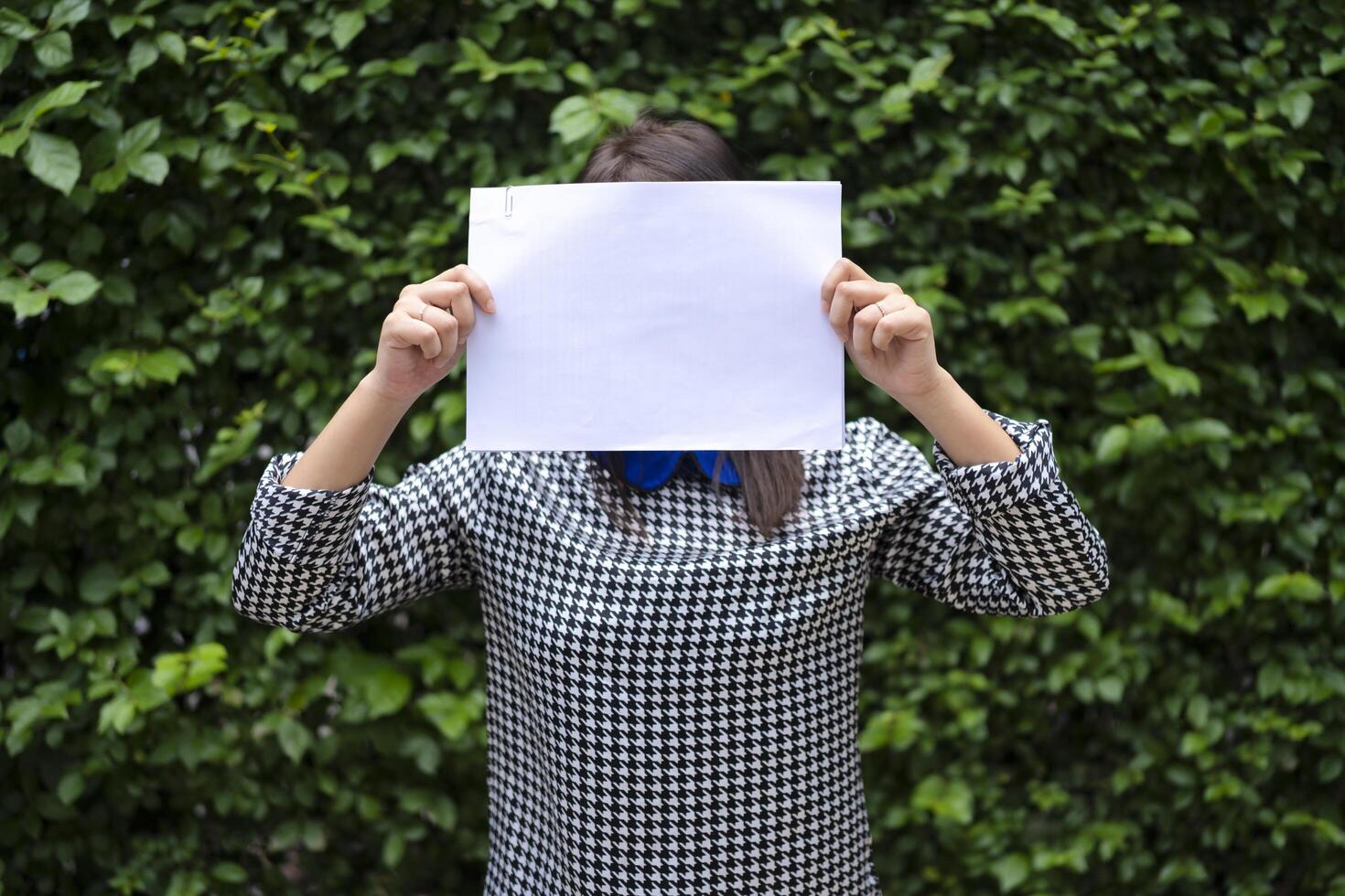 An Asian woman is standing with a white paper over her face. Able to put text for advertising media photo