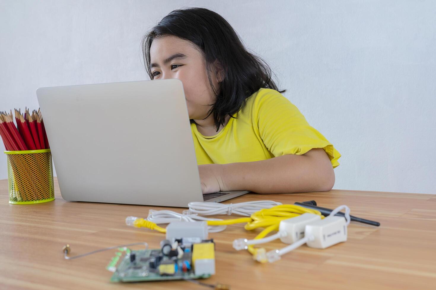 An Asian girl uses a laptop to install a robot controller from a plastic brick. Origins of education for children. STEM Education for kids. photo