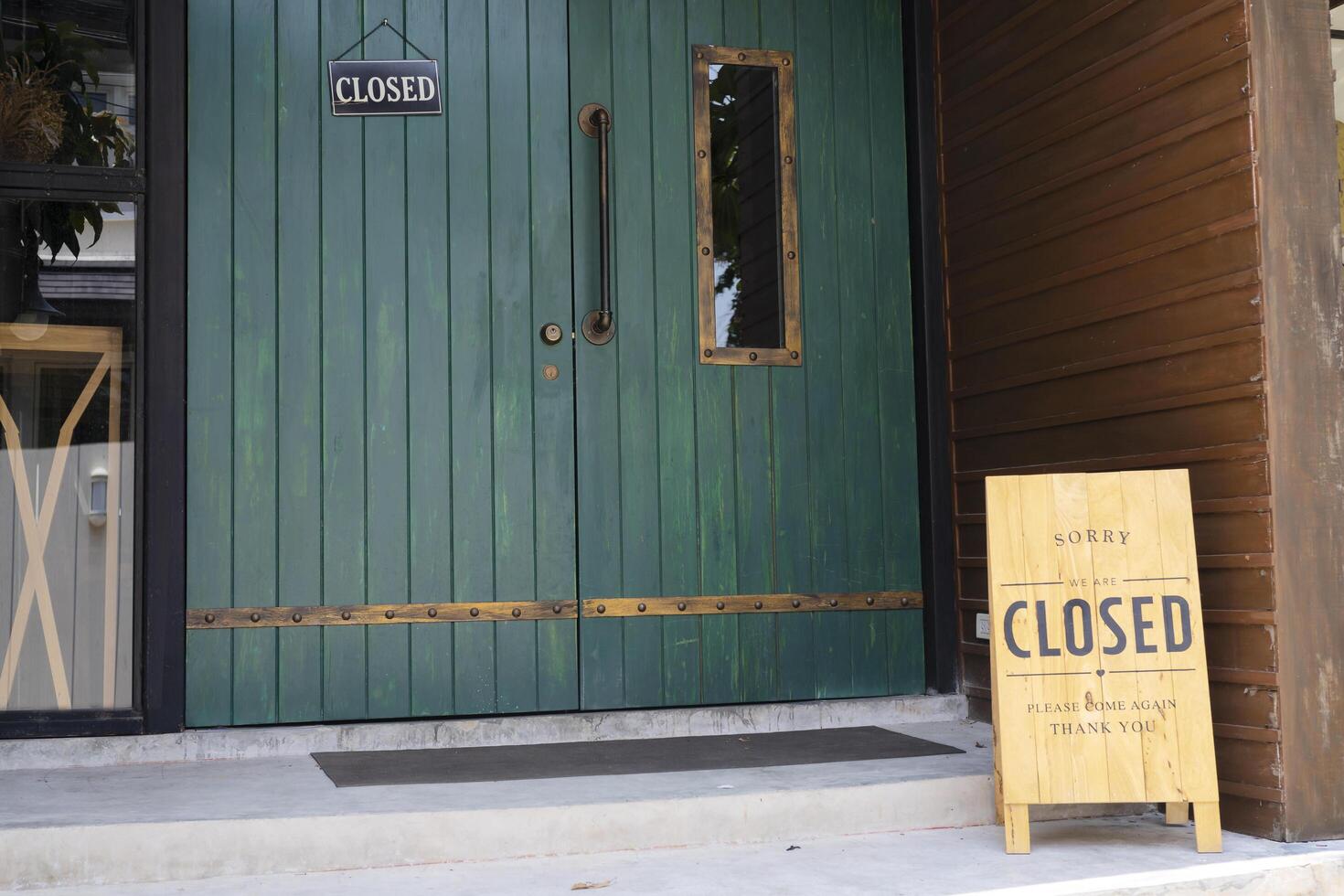 Closeup Wooden sign placed in front of the shop is labeled SORRY WE'RE CLOSED photo