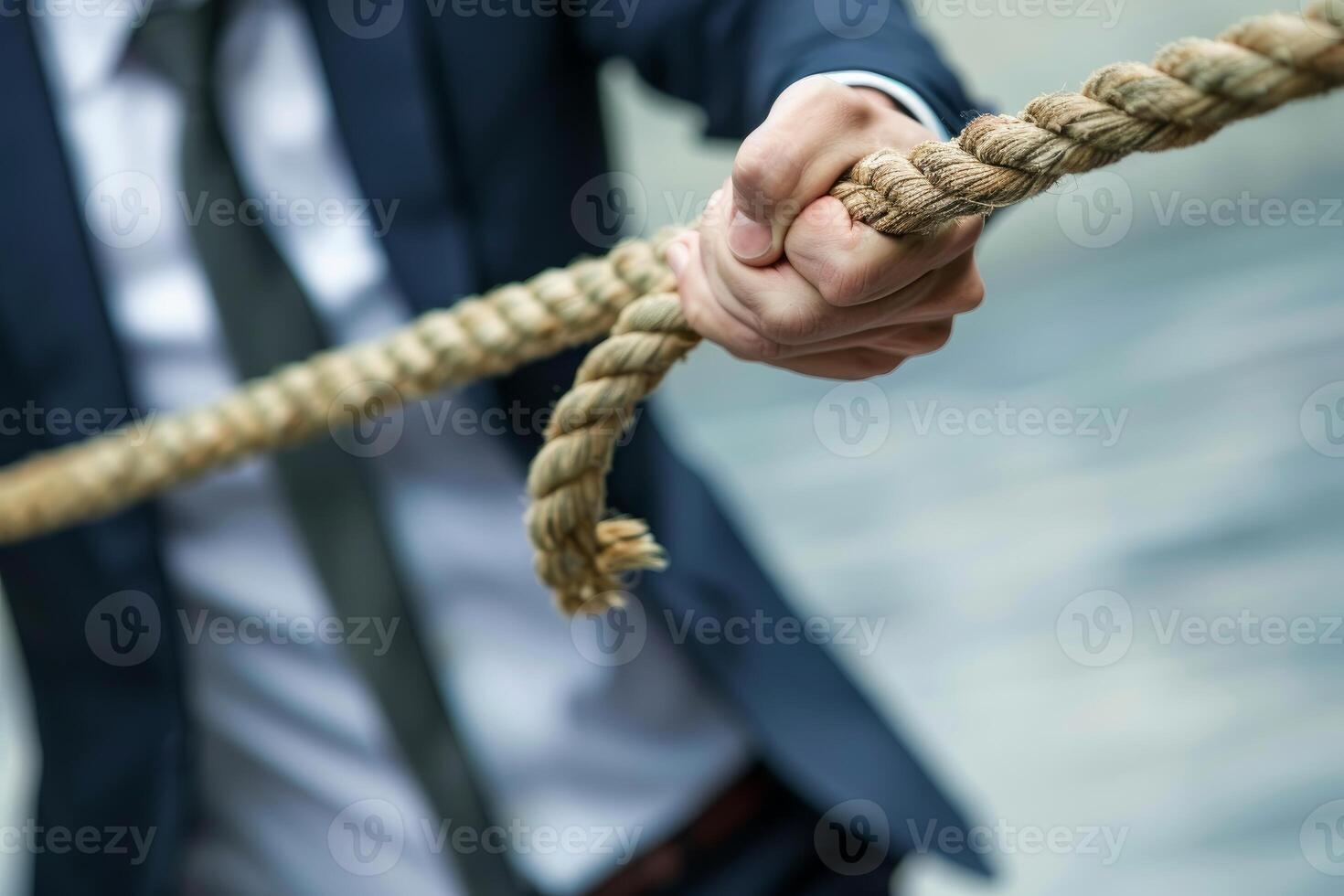 Businessman pulling a heavy rope in tug of war photo