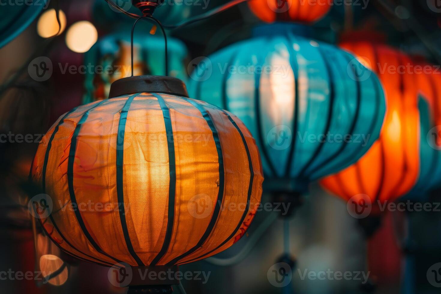 Closeup of glowing paper lanterns illuminating with warm light at dusk photo