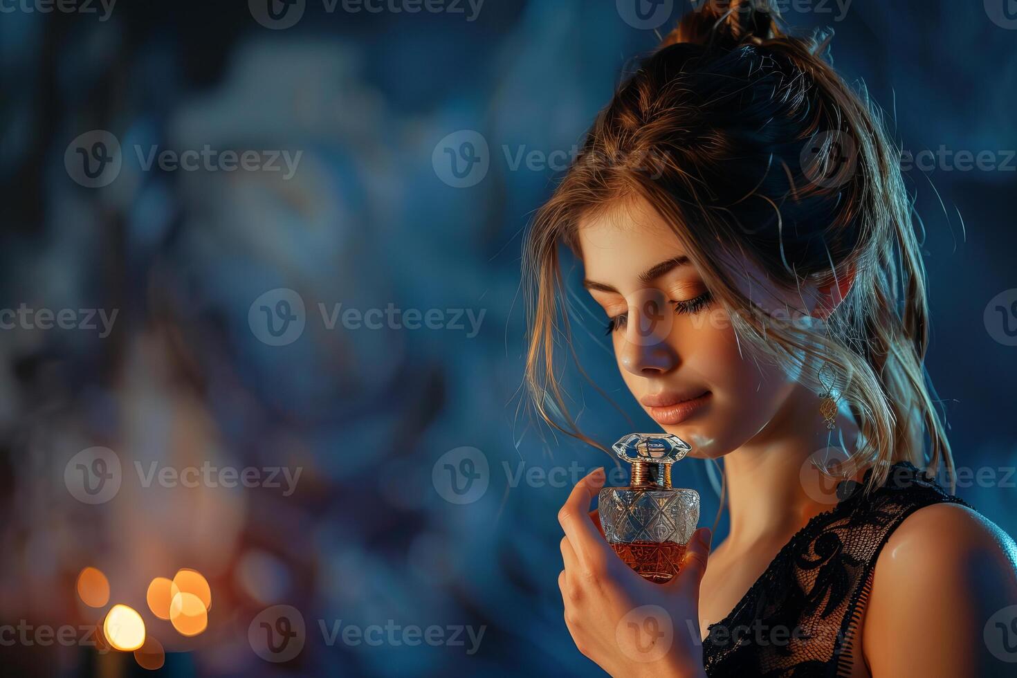 Young woman is holding a bottle of perfume and smelling its fragrance photo