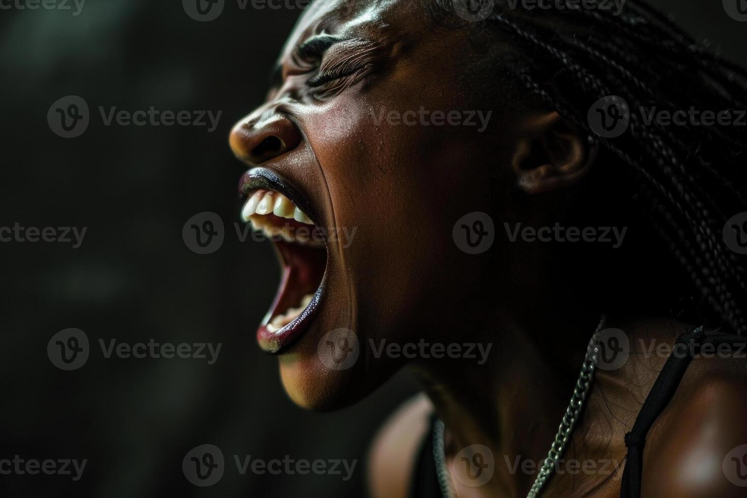 Young black woman with braids is screaming with her mouth wide open photo