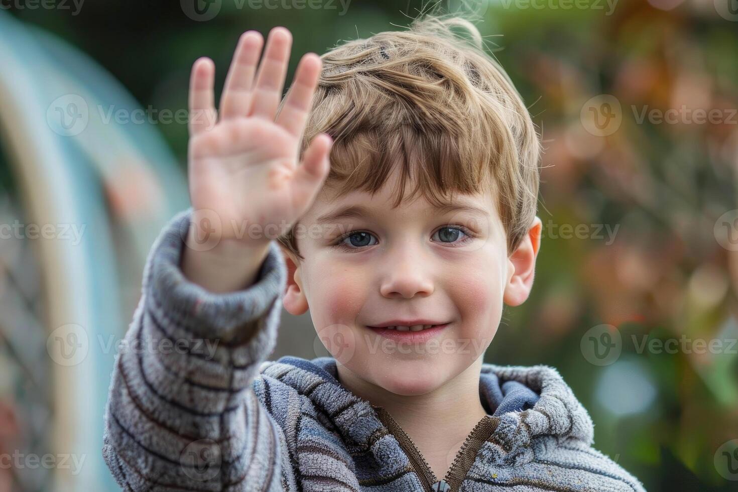 Young boy waving hello with five fingers raised photo