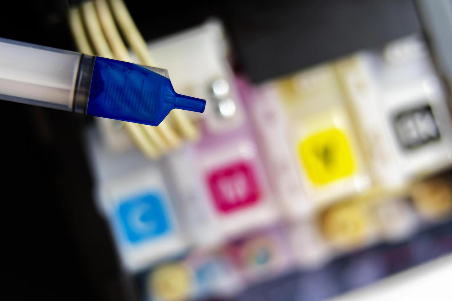 Closeup Refilling ink into a blue ink tank printer at office photo
