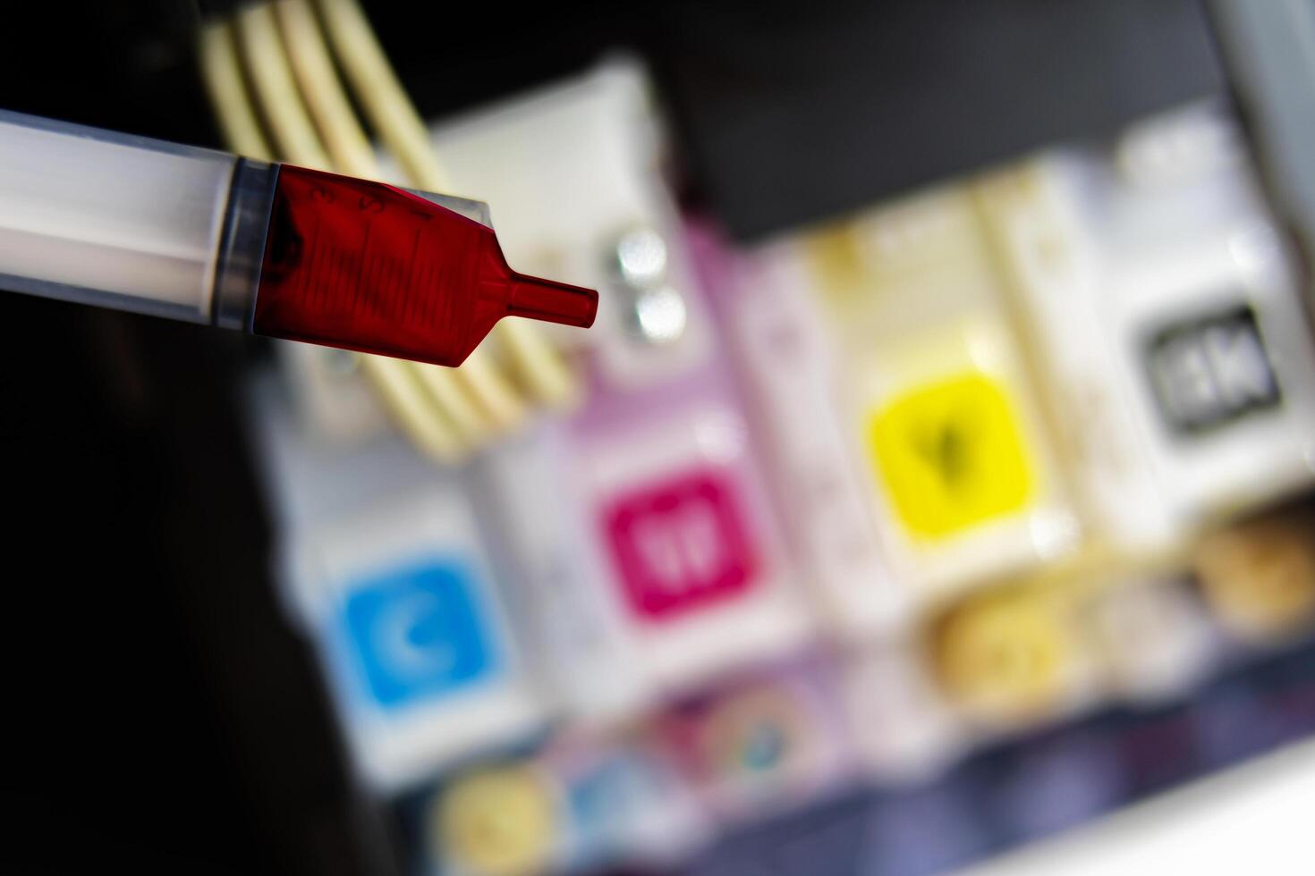 Closeup Refilling ink into a red ink tank printer at office photo