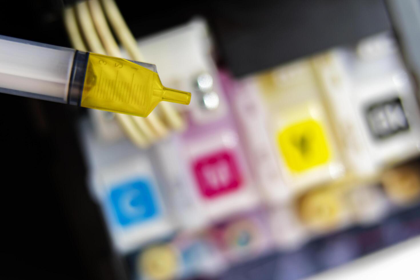 Closeup Refilling ink into a yellow ink tank printer at office photo